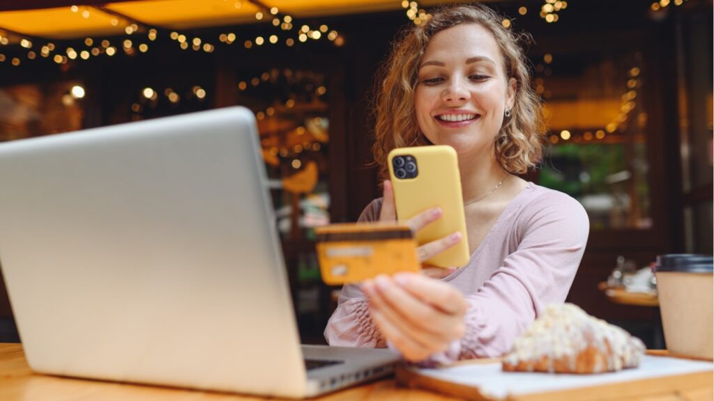 Woman holding credit card and using laptop