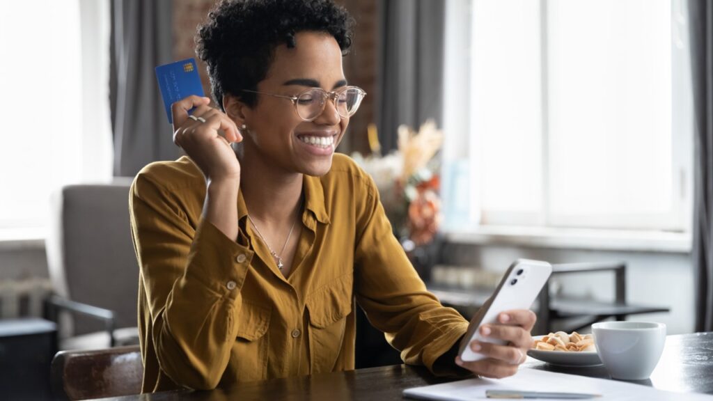 Woman smiling holding phone and credit card