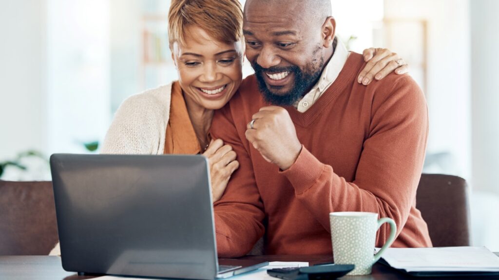 Couple celebrating in front of laptop