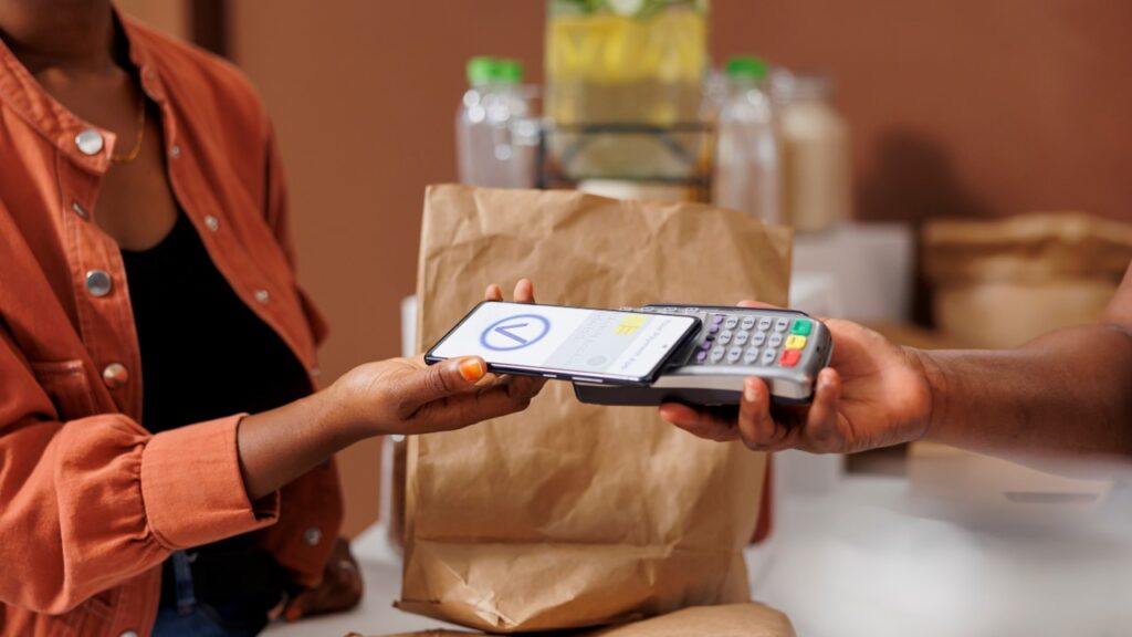 Hand using phone to pay for groceries