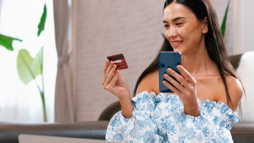 Woman smiling with credit card in one hand and phone on the other