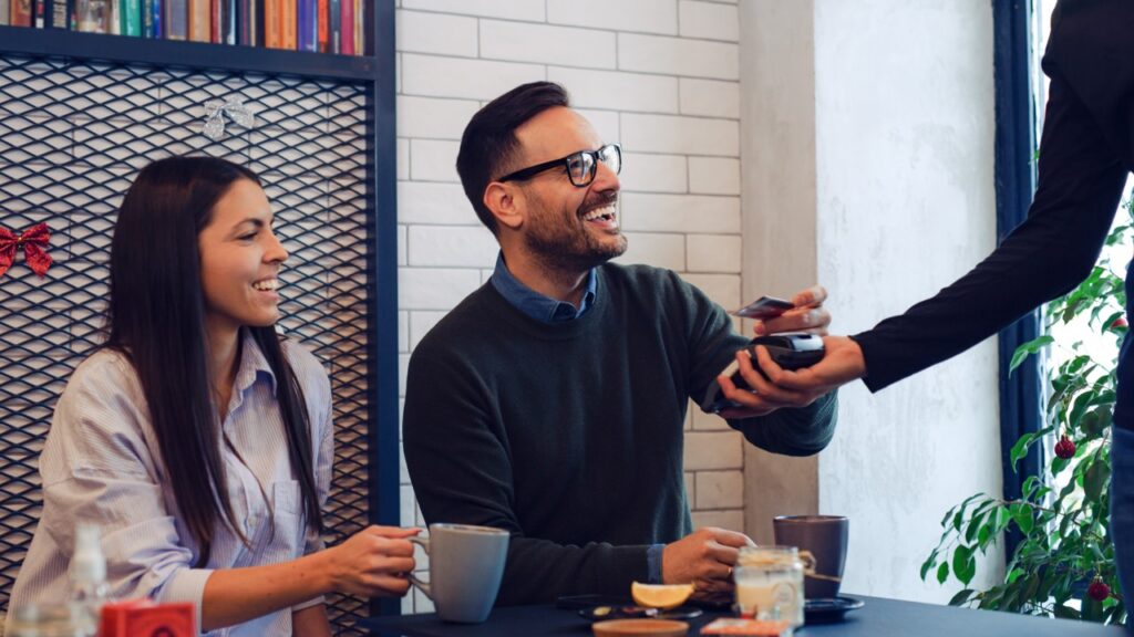 Happy man paying for coffee with credit card