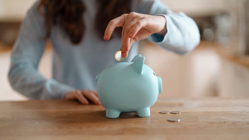 Hand putting coin in piggy bank