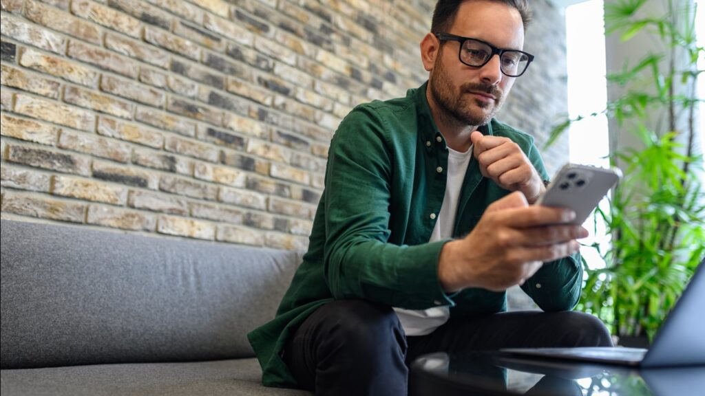 Man sitting on couch using phone